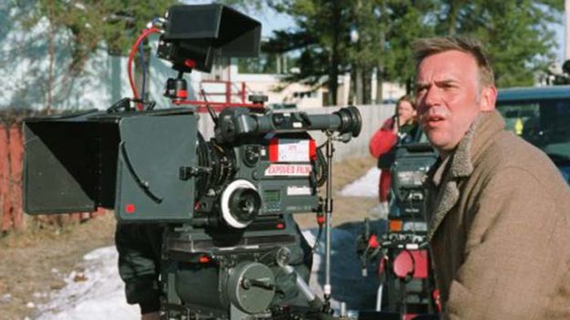 A middle-aged man stands next to a camera