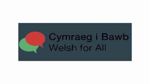 A green speech bubble overlaying a red speech bubble, with text beside it reading "Cymraeg i Bawb, Welsh for All"