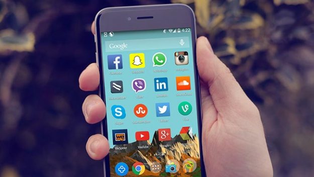 A phone held in a person's hand featuring app icons of major social media platforms