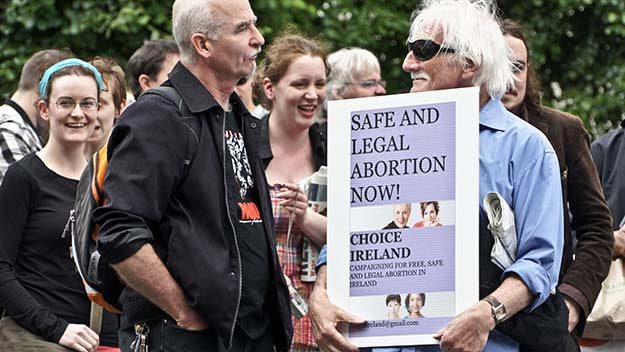 Men holding a sing reading Safe Legal Abortion at a rally for abortion rights