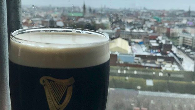 A foaming glass of dark beer against a window, part of the Guinness St Patrick's Day celebration