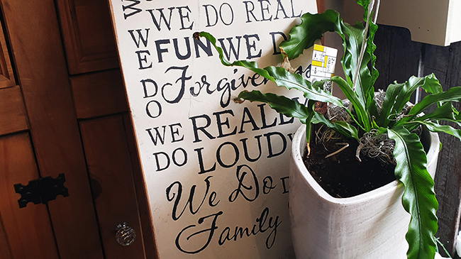 A typography board next to pot of plants.