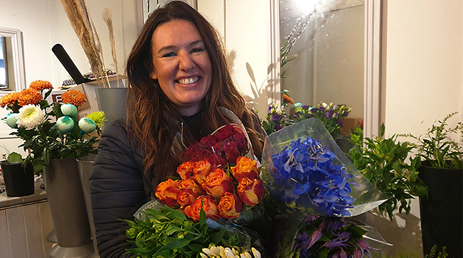 Kerry holding a bouquet of lowers at her workplace.