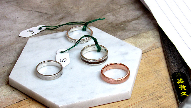 A collection of Cichocki's rings, from left to right: featuring Sterling silver (far left), Silver sand cast (top right), Sterling sand cast with marble inlay (middle right) and a rose gold sand cast (bottom right). Customers can send sand from their favourite beaches to be used and work one-on-one to create desired pieces. 