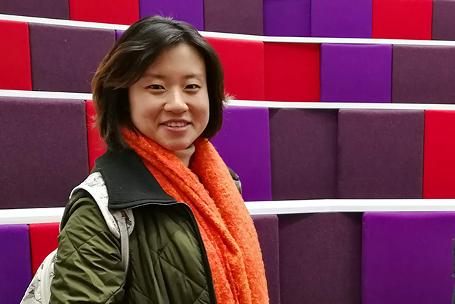 smiling student in lecture theatre with purple and red seats