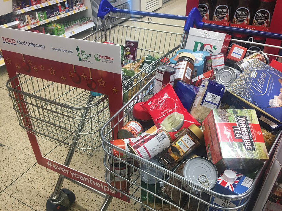 Shopping trolley containing food donations, including tinned soup, instant coffee, tea bags, pasta and rice.