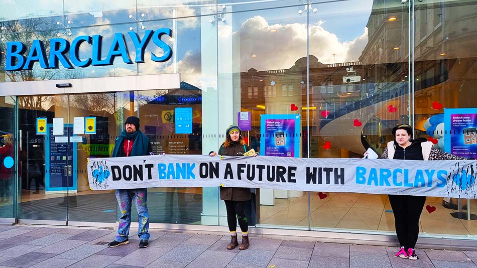 People holding banner in front of Barclays