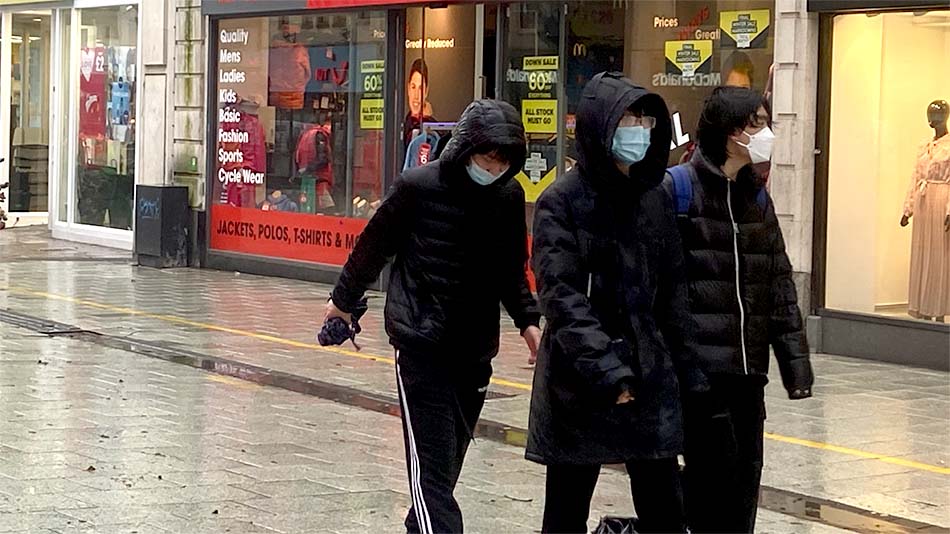People walking down the street wearing masks