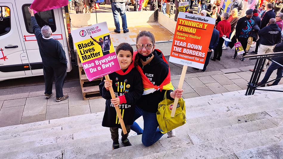 A mother and son holding BLM and Open Borders placards