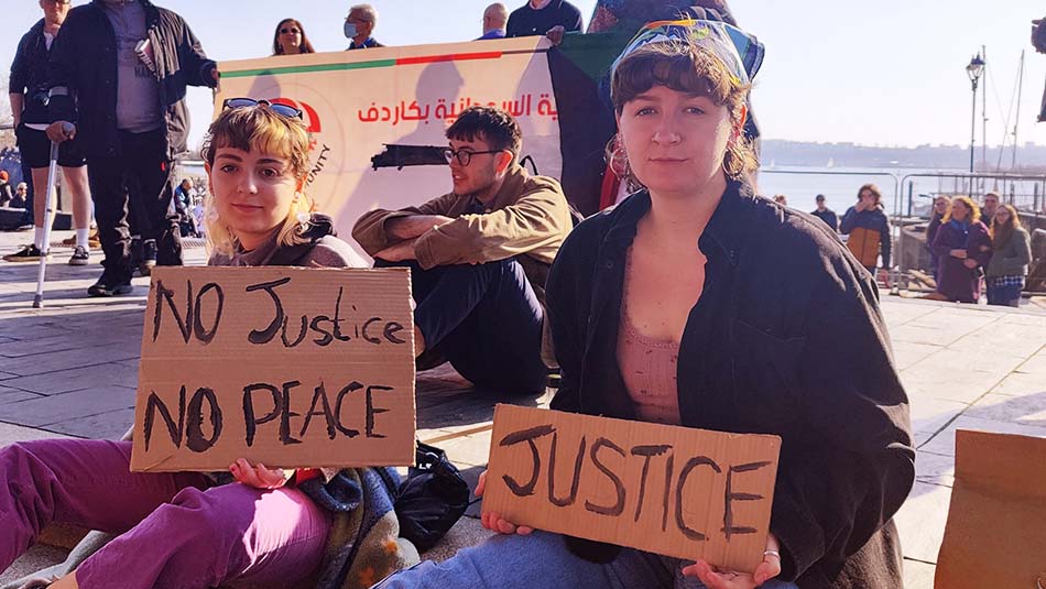 Activists holding placards saying 'No Justice No Peace' and 'Justice'