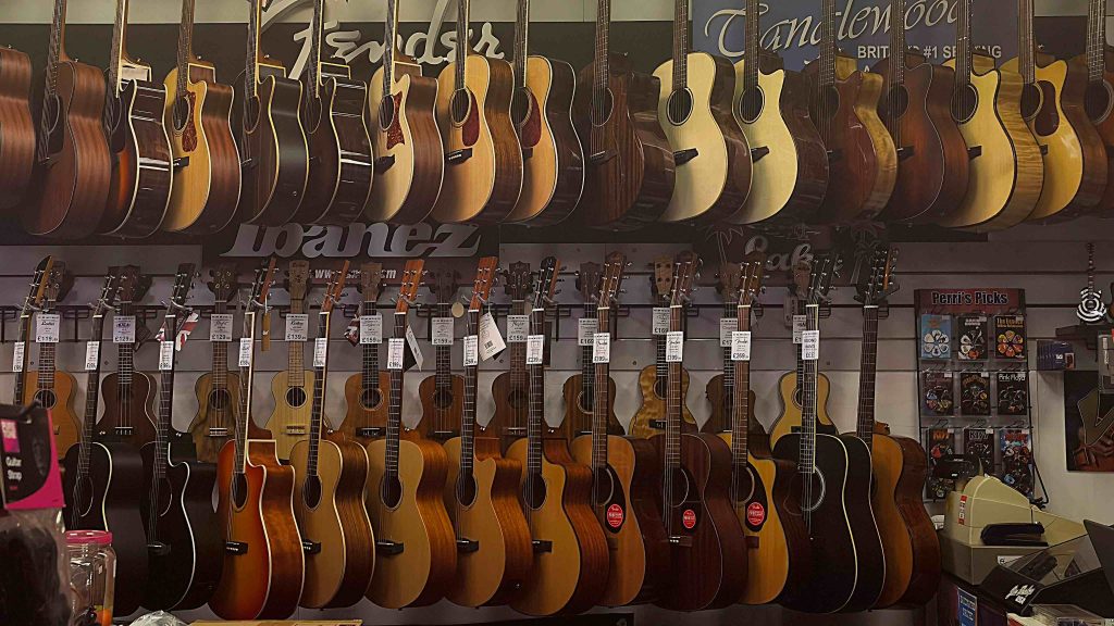 Many acoustic guitars in GM Music hang all over the walls and wait to be played.