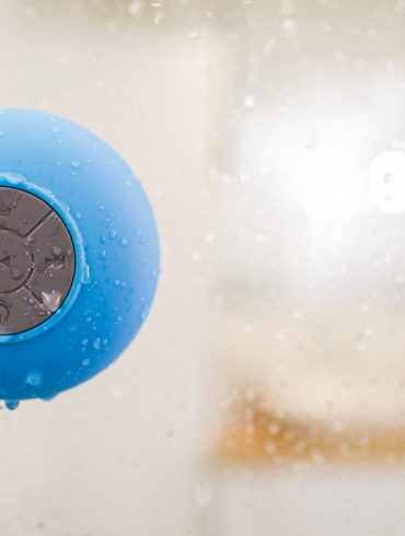 A picture of a speaker on the side of a shower, with water dropping from it