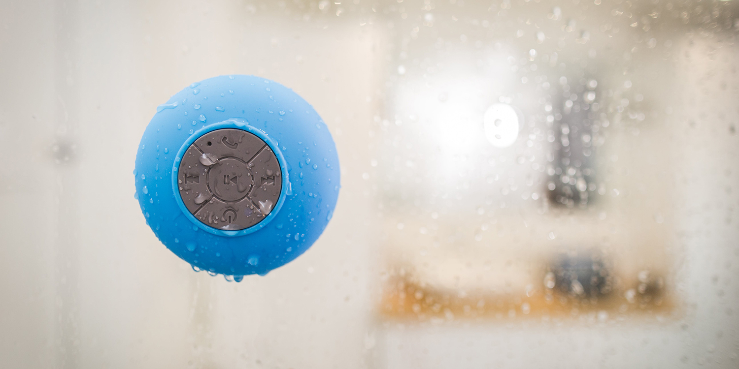 A picture of a speaker on the side of a shower, with water dropping from it