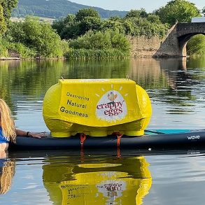 Activist Angela Jones swimming in the River Wye with a box saying 'Crappy Eggs'.