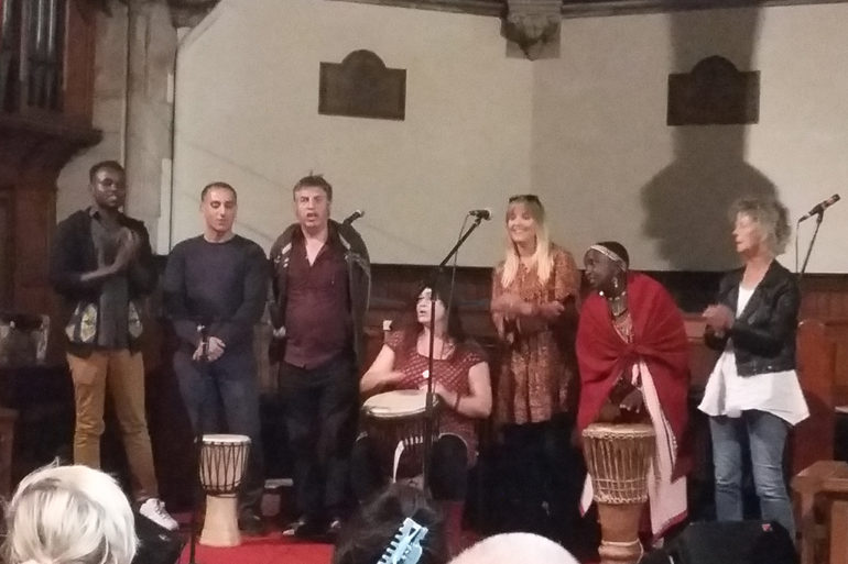A group of drummers and singers perform in a church hall.