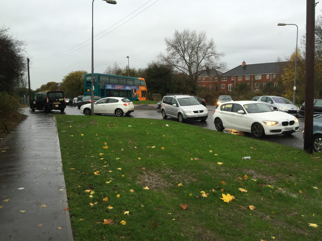 Cars parked on the roundabout at the end of Lawrenny Avenue obstructing a school bus.