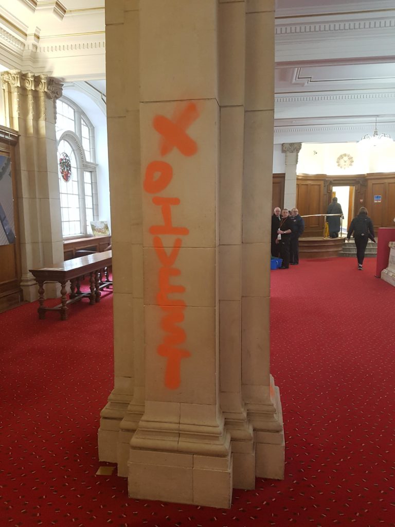 'Divest' sprayed onto a pilar in the Main Building of Cardiff University