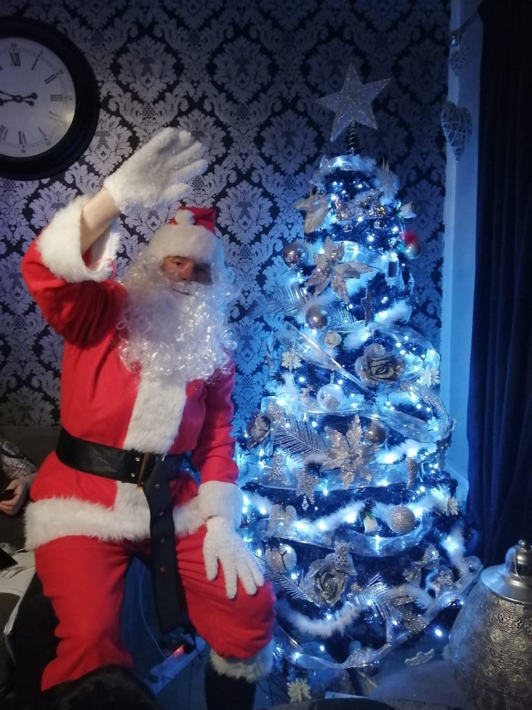 Jaylo Miles waving next to a Christmas Tree