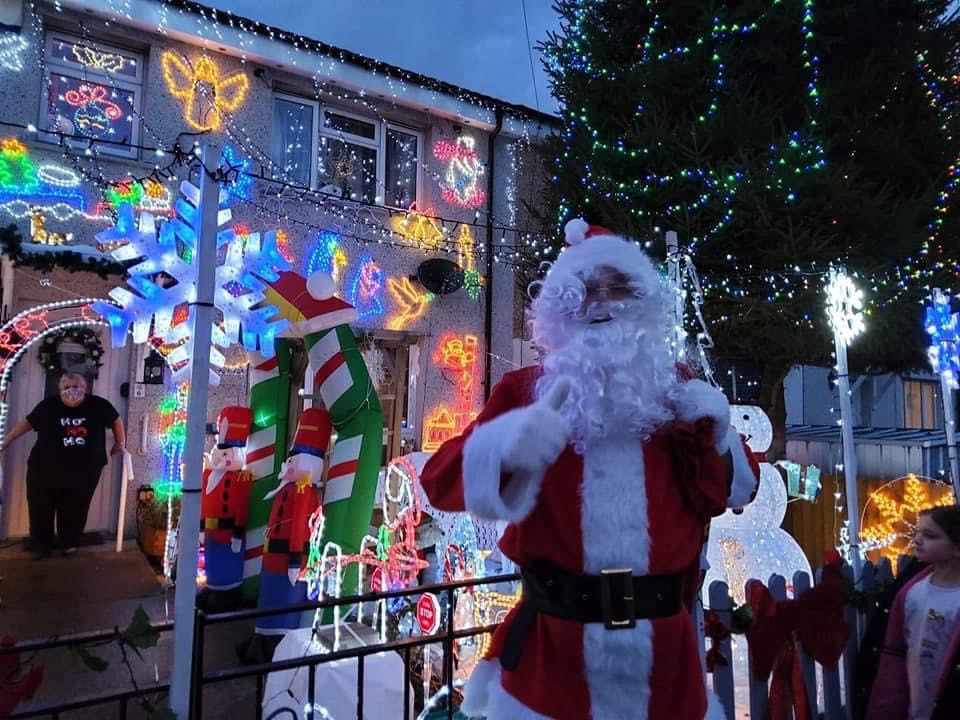 Jaylo Miles dressed as Santa Claus outside a decorated house.