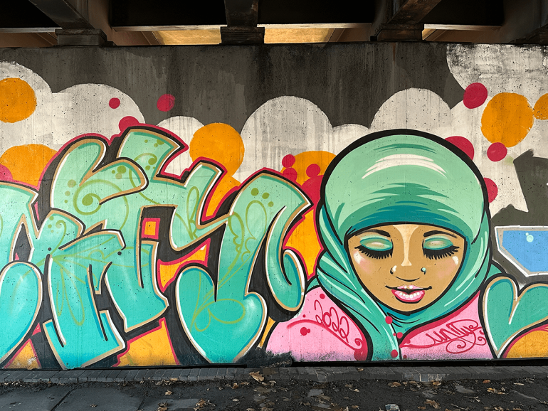 A mural of a girl wearing a hijab with the word 'unity' on a concrete wall