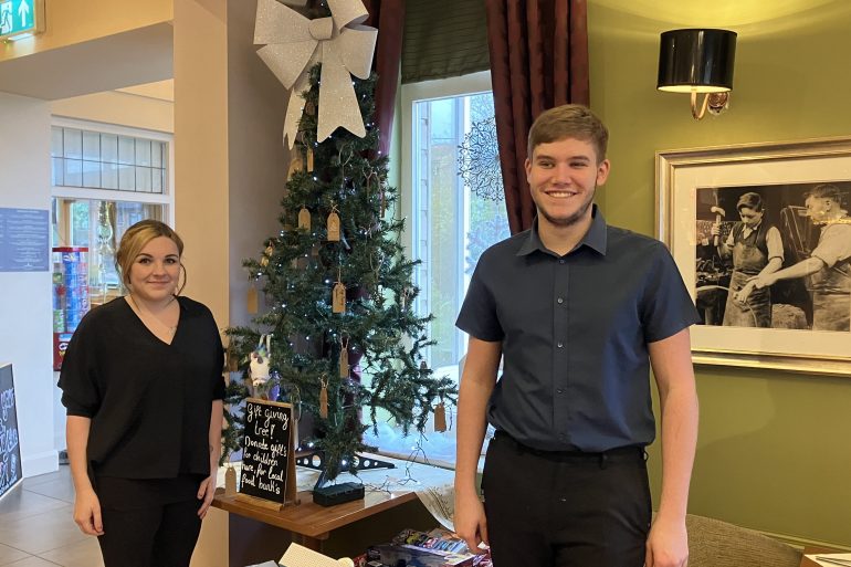 Carys and Mason from Coopers Carvery stand next to their gift tree.