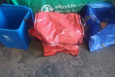 A blue plastic caddy, a red sack and a blue sack