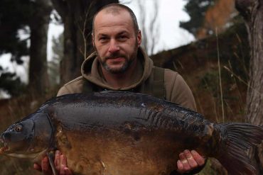 A man looking proud holding a huge fish up.