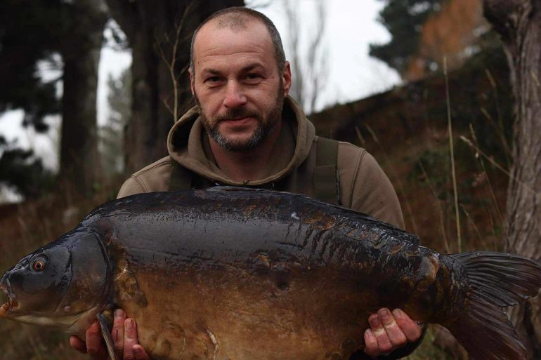 A man looking proud holding a huge fish up.