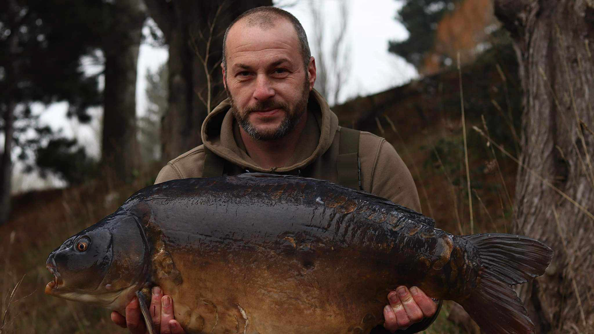 A man looking proud holding a huge fish up.