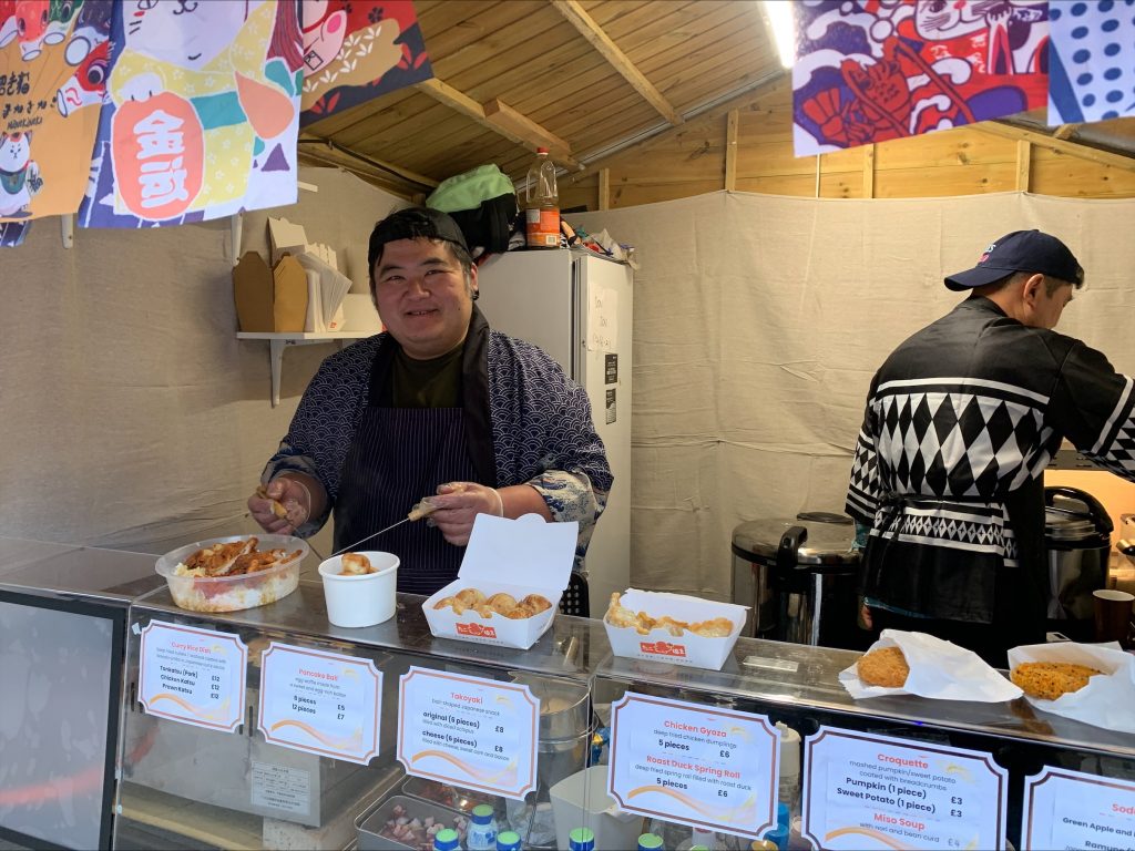 Hong Kong-born David Chan, 42, serves customers food at his Cardiff Christmas market stall