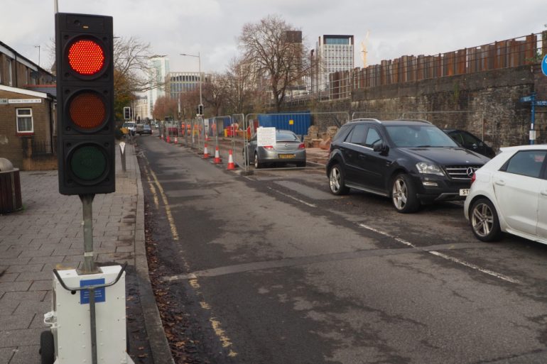 A red traffic light controlling traffic by roadworks on Bute Street