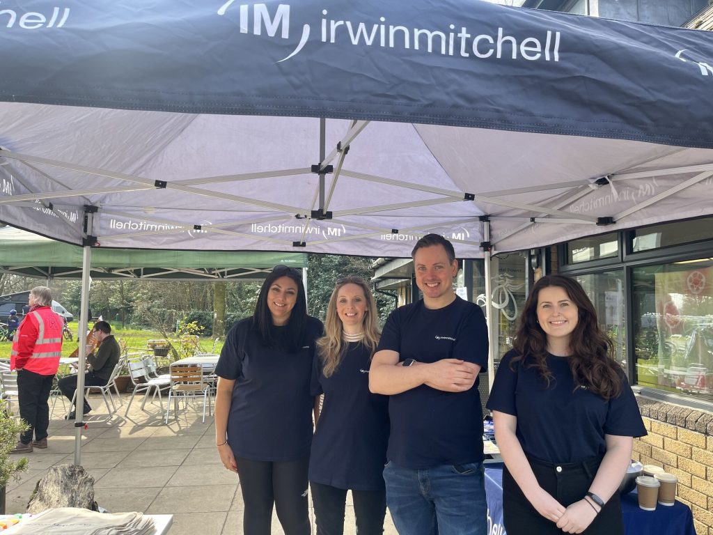 Four members of staff from Irwin Mitchell, stood under a blue gazebo. 